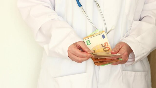 Treatment costs in the European Union, Private medical practice, additional illegal or legal income of a doctor, Concept. The doctor counts a large sum of euros