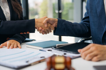 Lawyer shaking hands with client after discussing final contract agreement.