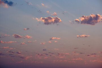 Sunset with pink and orange clouds in the sky, as the sun's rays gently pass through them in the evening.