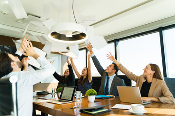 Businesspeople wrapping up a big project and celebrating by throwing papers in the air