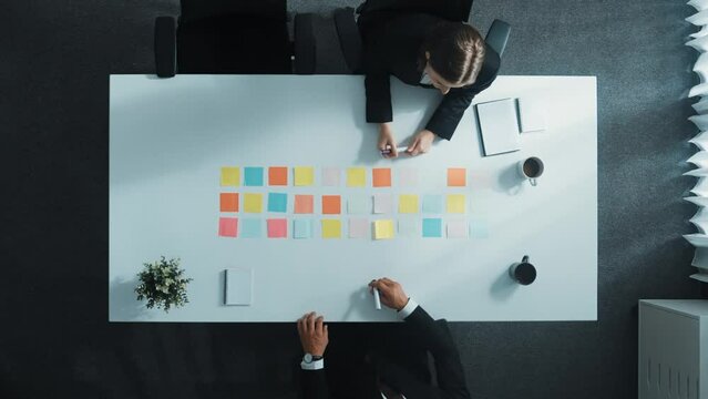 Top view of professional business people making agreement and brainstorm marketing idea or plan by using colorful sticky notes on table with coffee and paper placed on at meeting room. Directorate.
