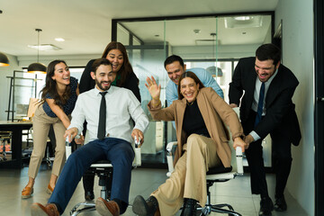 Group of businesspeople having fun in the office and racing in chairs