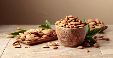 Fototapeta na wymiar Almond nuts in wooden dishes on a ceramic table.