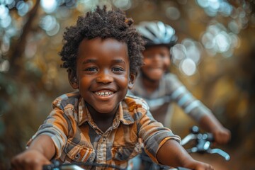 Young boy with a big smile riding his bicycle in a park with a blurred friend in the background - obrazy, fototapety, plakaty