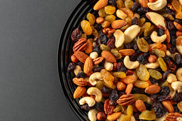 Mix of dried nuts and raisins on a black background.