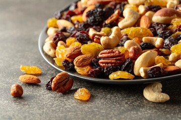 Mix of dried nuts and raisins on a rustic background.