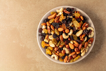 Mix of dried nuts and raisins on a beige background.