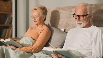 Elderly couple reading books in bed