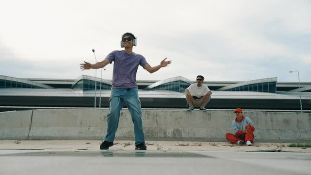 Group of asian break dancer perform street dance with multicultural friend support and moving hip hop music. Attractive handsome hipster practice b boy dance at street. Outdoor sport 2024. Sprightly.