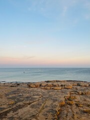 Natural pastel colors of the sky at the ocean, rocky ocean bay, purple heaven 