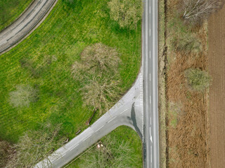 Drone top down view of an empty, straight country road seen near an empty side road an and junction. Located in the heart of the English countryside.