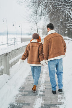 Love romantic couple lovestory. Brutal bearded man, bright red-haired girl woman in winter park. Romantic date, kissing, hugging. Walking, having fun. Stylish clothes, red sheepskin coat, jacket, hat