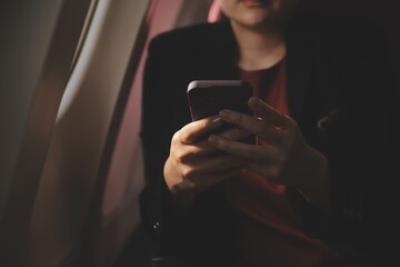 Blonde female tourist checking incoming notification on smartphone sitting on seat of airplane with...
