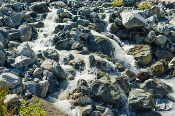 small shallow beautiful alpine stream with a fast flow and stones