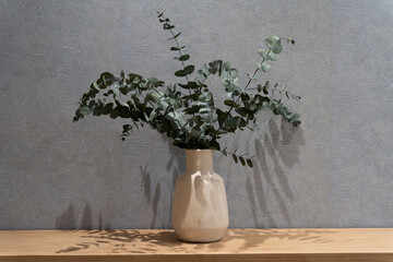 A vase with a bunch of green leaves in it sits on a shelf