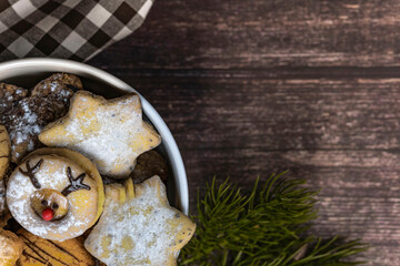 Weiße Porzellanschale mit Weihnachtskeksen auf dunklem Holzhintergrund, Draufsicht, horizontal