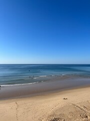 Fototapeta na wymiar Sandy ocean beach, shoreline, clear blue sky, blue seascape horizon 