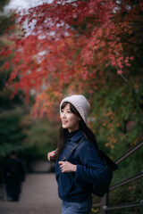 Asian woman in casual dress embraces the beauty of fall in Kyoto, enjoying a holiday filled with friends, smiles, and colorful foliage by the lake. A cheerful and scenic journey.