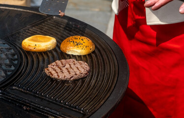 A burger bun is cooked on a red-hot grill.