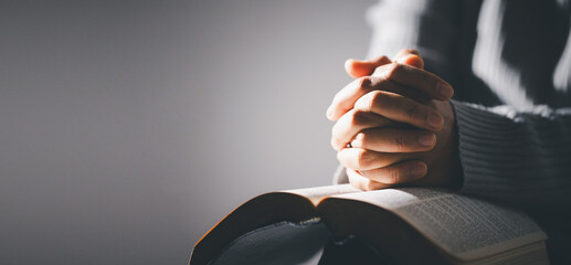 Hands folded in prayer on holy bible in church concept for faith, spirituality and religion....