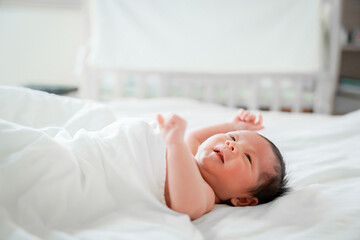 Obraz na płótnie Canvas male newborn baby Is a person of Asian ethnicity Lying in the bedroom on a white bed