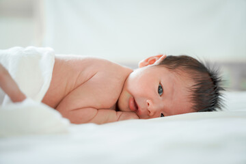 Fototapeta na wymiar male newborn baby Is a person of Asian ethnicity Lying in the bedroom on a white bed