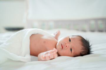 male newborn baby Is a person of Asian ethnicity Lying in the bedroom on a white bed