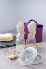 Two bottles of expressed breastmilk on a work desk. Mother working and taking a break to express...