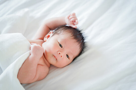 male newborn baby Is a person of Asian ethnicity Lying in the bedroom on a white bed