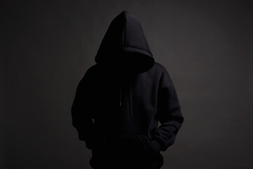 Man in Black Hood posing in dark studio. Boy