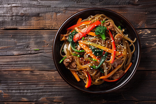 japchae or stir-fried Korean vermicelli noodles with vegetables and pork topped with white sesame - Korean traditional food style