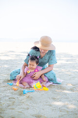 Mother and girl playing in the sand on the beach, Pattaya, Thailand,Mother with children playing with sand on beach