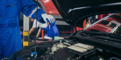 Close up mechanic hand checking oil level in the car engine. after repair service concept, copy space