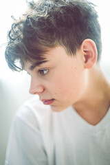Portrait of a handsome teenage boy in white t-shirt. No smile, looking away from camera.