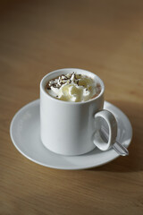 Eine weiße Tasse mit heißer Schokolade mit mit Sahne und Schokostreusel. 