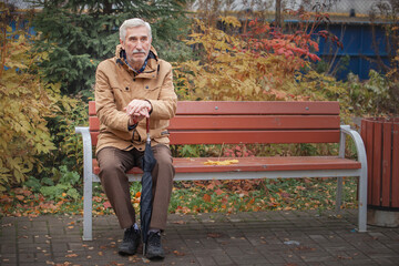 old gentleman sitting on a bench in the autumn park alone
