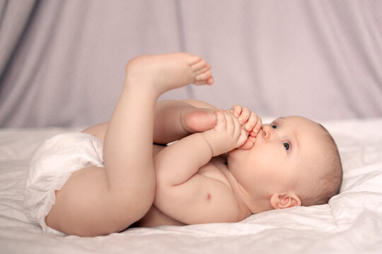 Closeup portrait of cute baby girl taking her feet in her mouth, reaction of Bacillus Calmette Guerin or BCG vaccination on left shoulder.