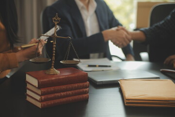 Justice and Law concept. Legal counsel presents to the client a signed contract with gavel and legal law or legal having team meeting at law firm in background