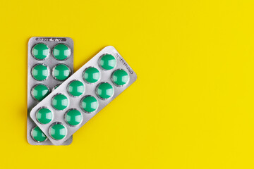 two blisters with green tablets on a yellow background with a copy space