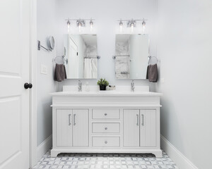 A bathroom with a white vanity cabinet, marble pattern tile flooring, and polished chrome light...