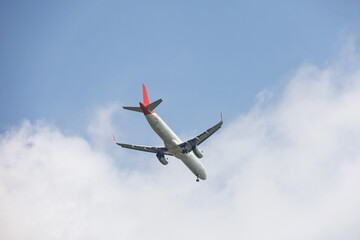 Airplane flying in sky with white clouds. Passenger plane at flight, travel concept