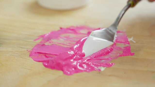 Artist mixing paints for making new artwork. Female artist preparing for draw a picture. Unrecognizable artist mixing acrylic paints using palette knife. Art concept. Close-up in 4K, UHD