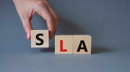 SLA - Service Level Agreement. Wooden cubes with word SLA. Businessman hand. Beautiful grey background. Business and Service Level Agreement concept. Copy space.