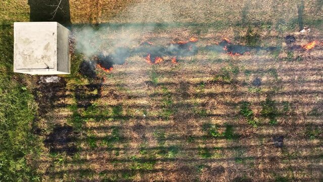 Topdown drone shot of burning crop residue or stubble burning in a farm in Uttar Pradesh, India. Burning dry grass after harvest