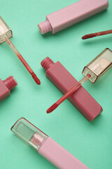 Beautiful lip glosses on a mint background. Vertical photo