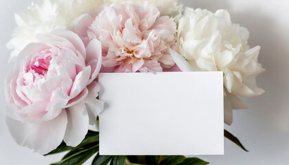 Mock up of blank white paper card and bouquet of peonies. Spring flowers.