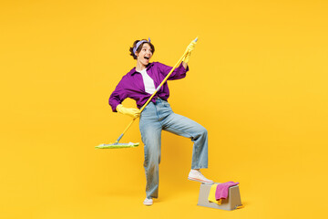 Full body young woman wears purple shirt casual clothes do housework tidy up pov play guitar hold mop bucket water wash floor isolated on plain yellow background studio portrait. Housekeeping concept.