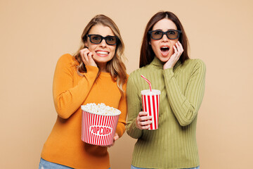 Young scared friends two women they wear orange green shirt casual clothes 3d glasses watch movie...