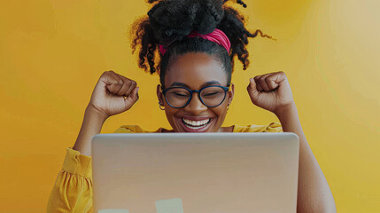 A woman is smiling and holding her hands up in the air while looking at a laptop. The laptop is open and there are several stickers on it