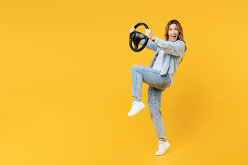 Fototapeta na wymiar Full body side view young woman she wears blue shirt white t-shirt casual clothes hold steering wheel driving car raise up leg isolated on plain yellow background studio portrait. Lifestyle concept.